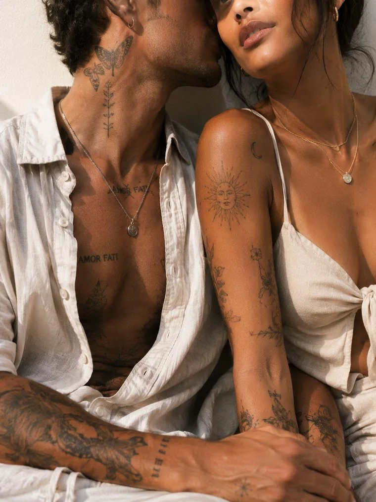 A couple with fine-line tattoos across their necks, chests and forearms